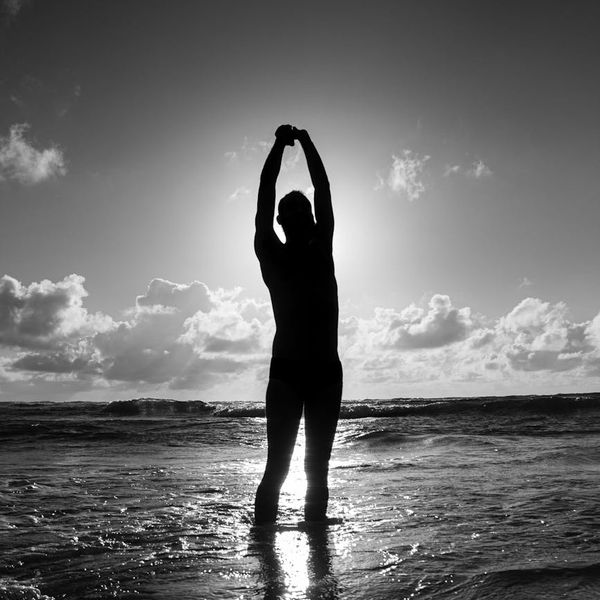 A silhouette of a person stretching during sunrise, conveying a sense of peace and energy.